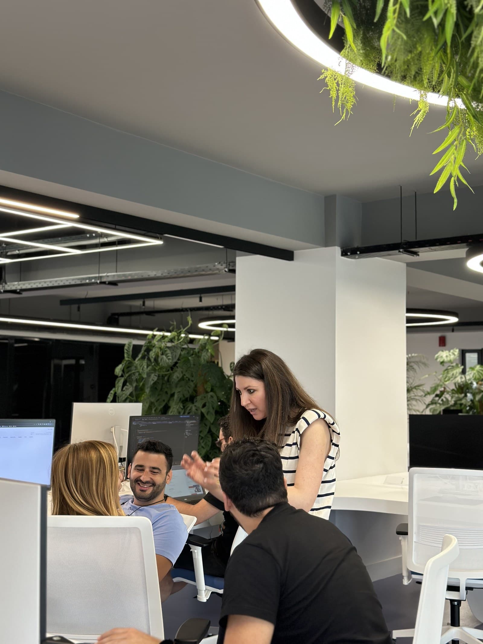 ATCOM teammates talking at a plant-filled desk in the office