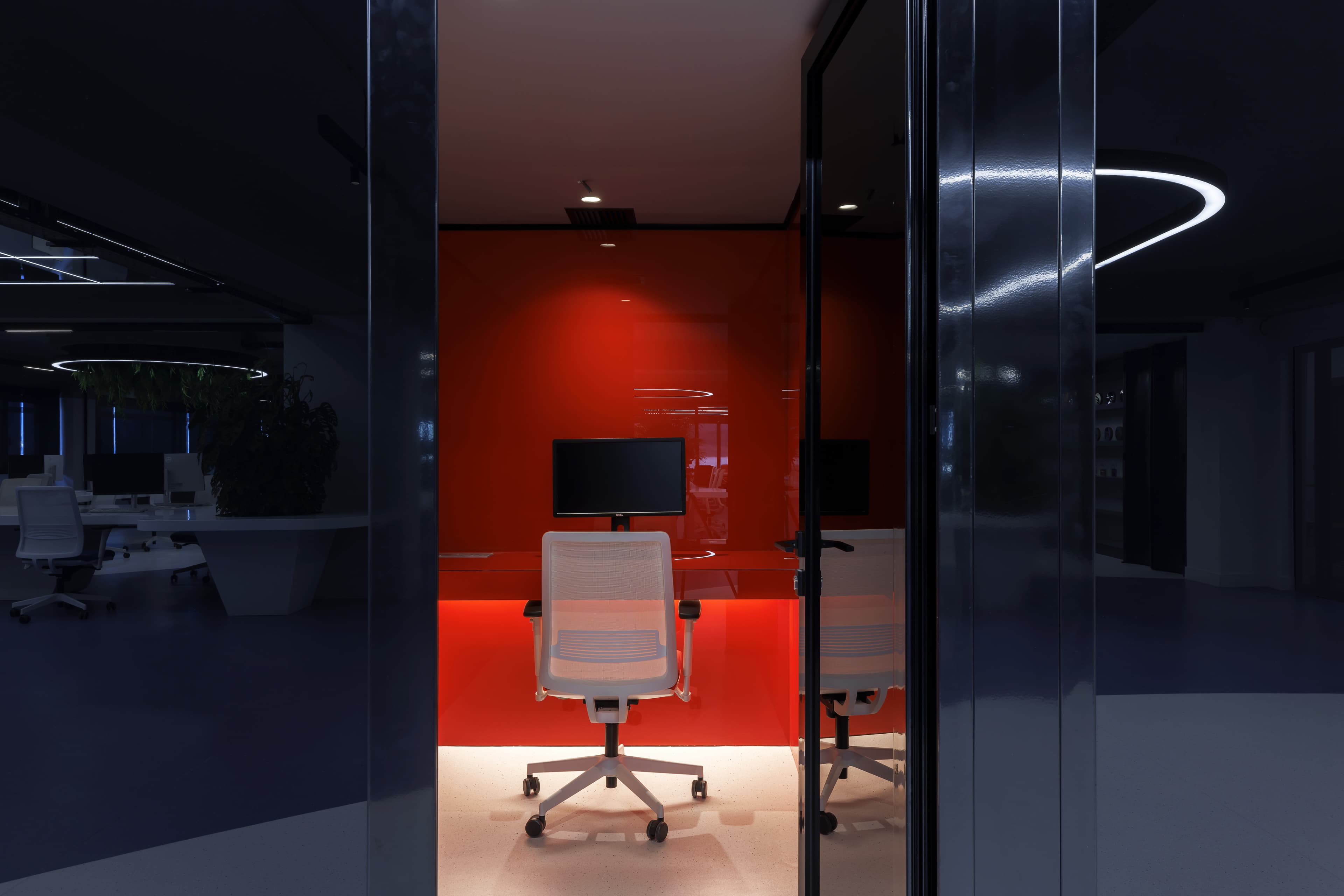 A red-lit ATCOM workspace with white ergonomic chairs and a monitor