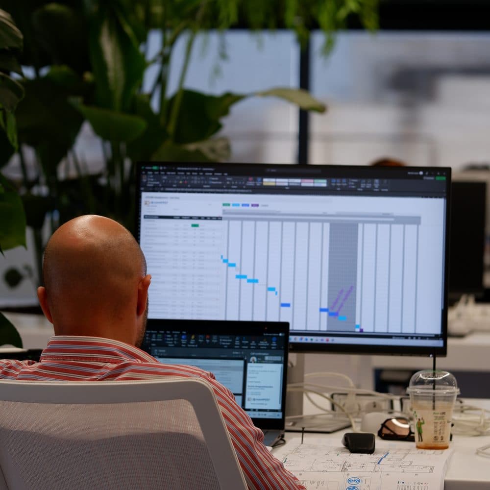 An ATCOM engineer reviewing a project timeline on a large monitor