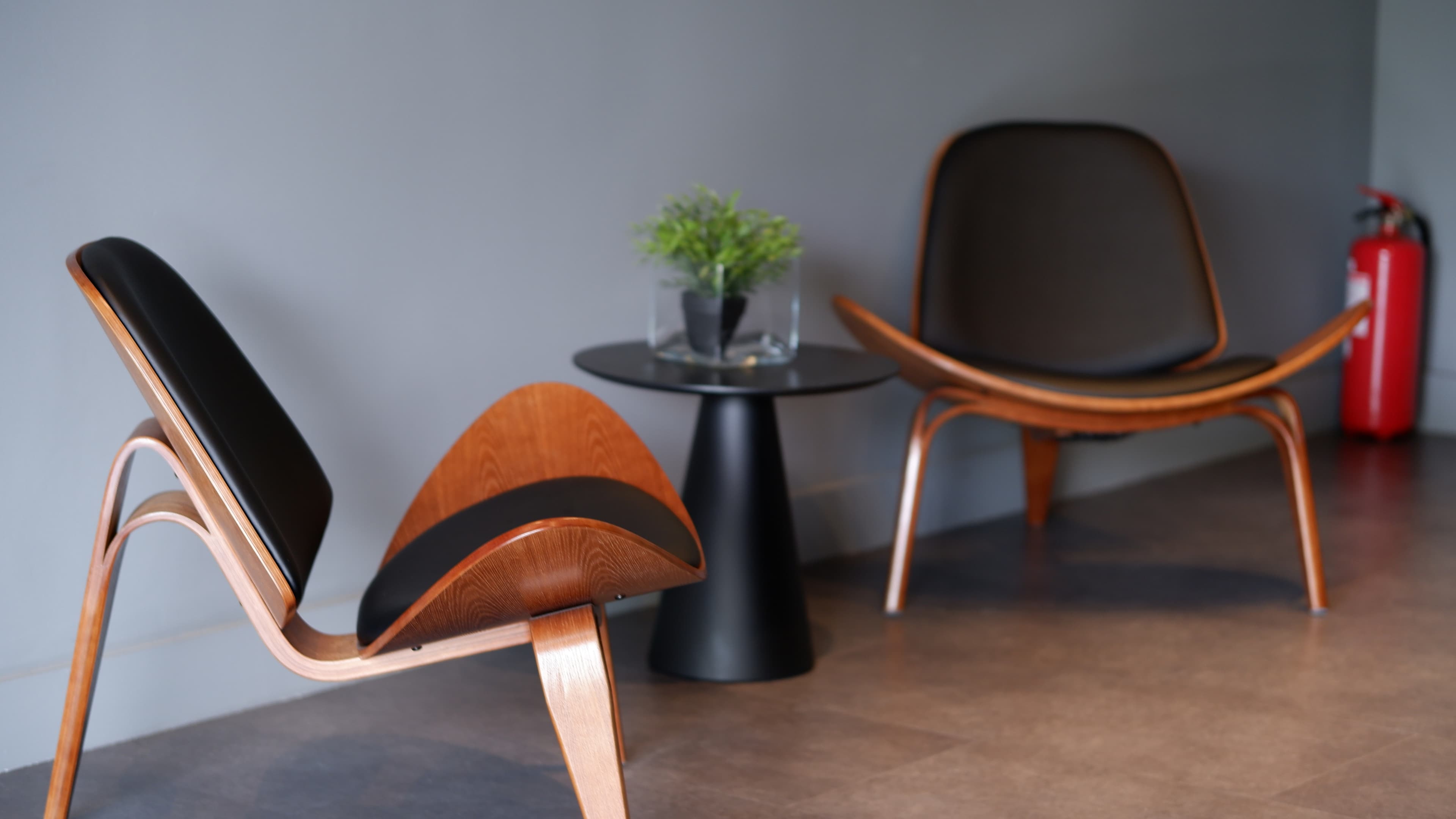 Two mid-century designer lounge chairs by a plant and side table in the ATCOM office